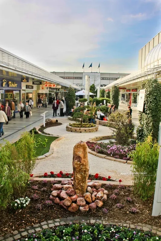 Ausstellungsgarten mit runder Pflanzfläche und Blumenbeeten in der Ladenstraße des Ruhrparks Bochum